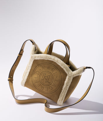 Tan handbag with shearling lining on a white background