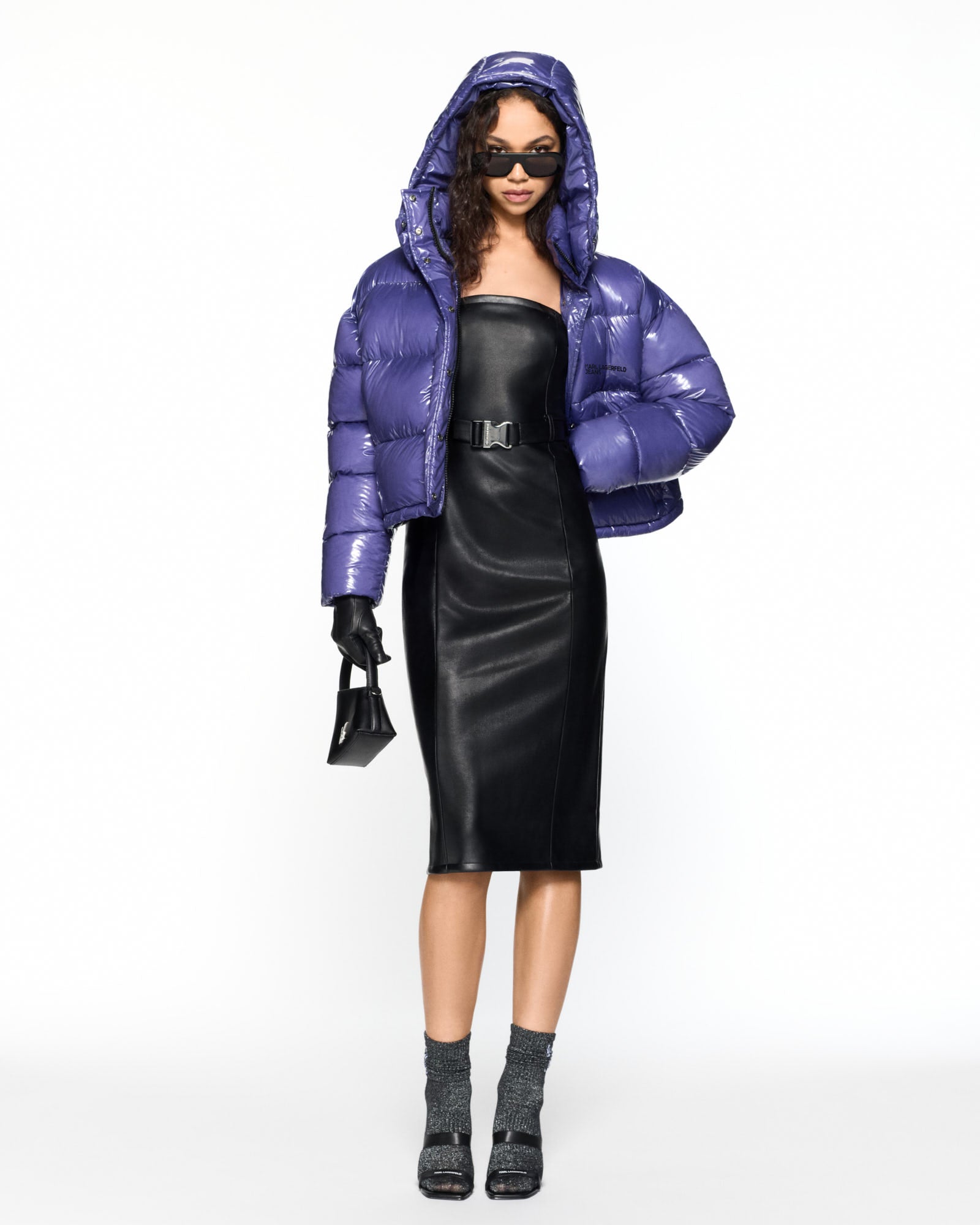 Person wearing a purple puffer jacket and black outfit on a white background