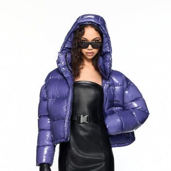 Person wearing a shiny purple puffer jacket and black outfit on a white background